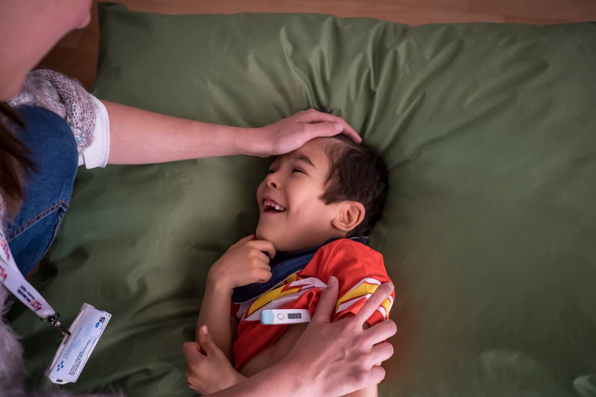 Una enfermera de cuidados paliativos toma la temperatura a un niño en una visita domiciliaria. FOTO: Ariadna Creus y Àngel Garc�a (Banc Imatges Infermeres).